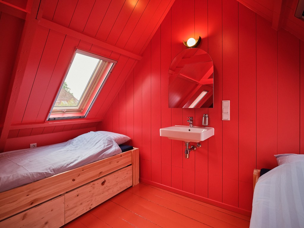 Rode zolderkamer met houten bed en rode muren op zolder in Het Molenhuis