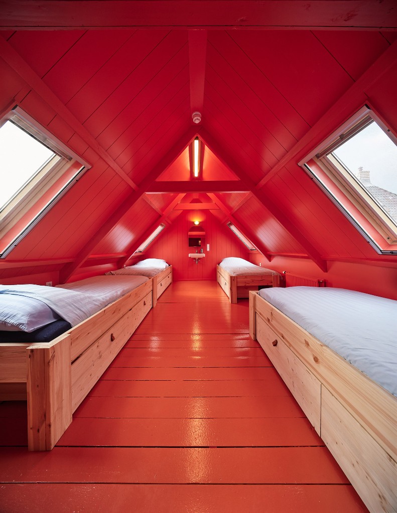 Rode zolderkamer met houten bedden en dakramen in Het Molenhuis