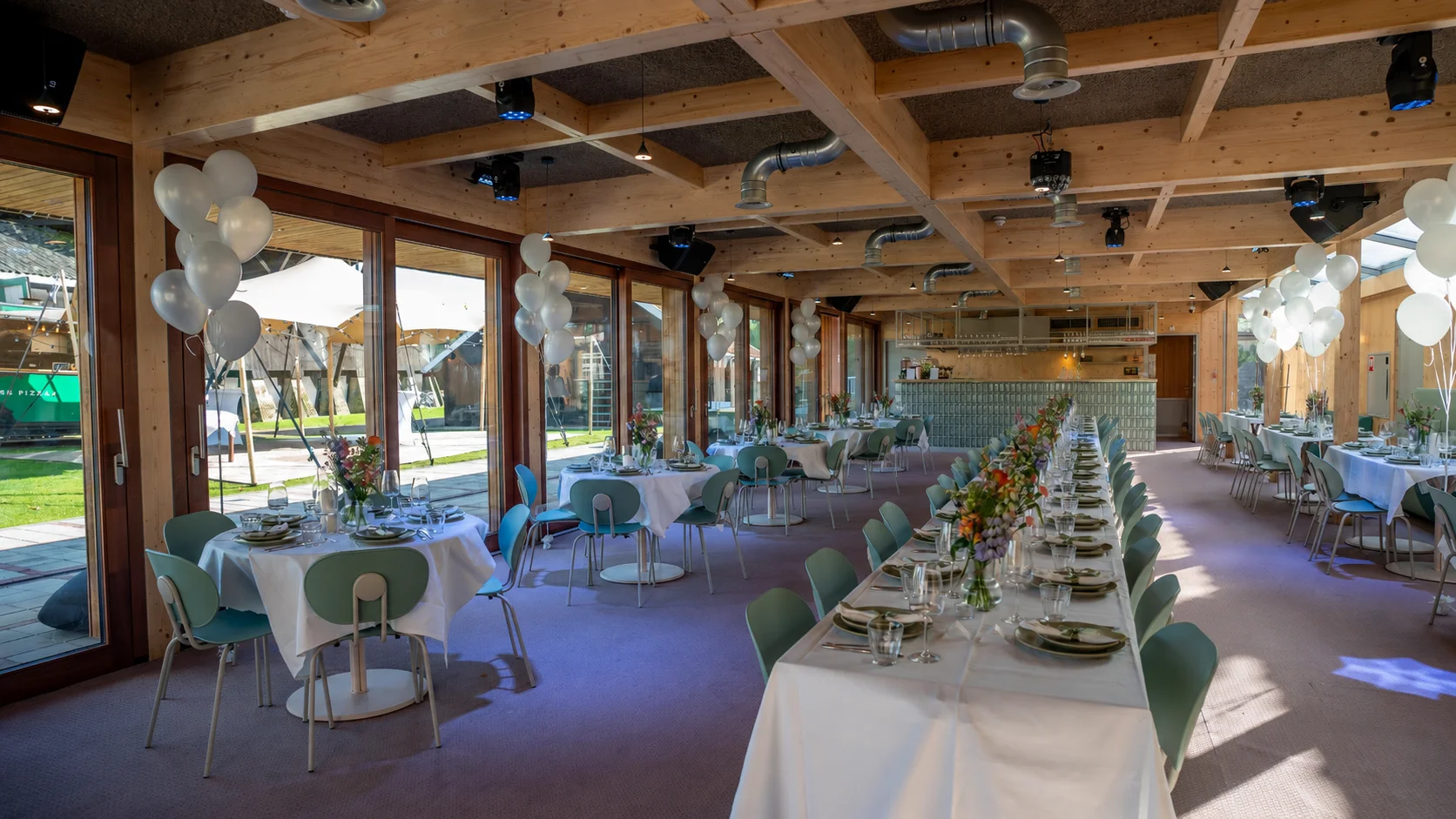 Het paviljoen van Het Molenhuis: houten feestruimte met gedekte tafels en uitzicht op de stretchtent